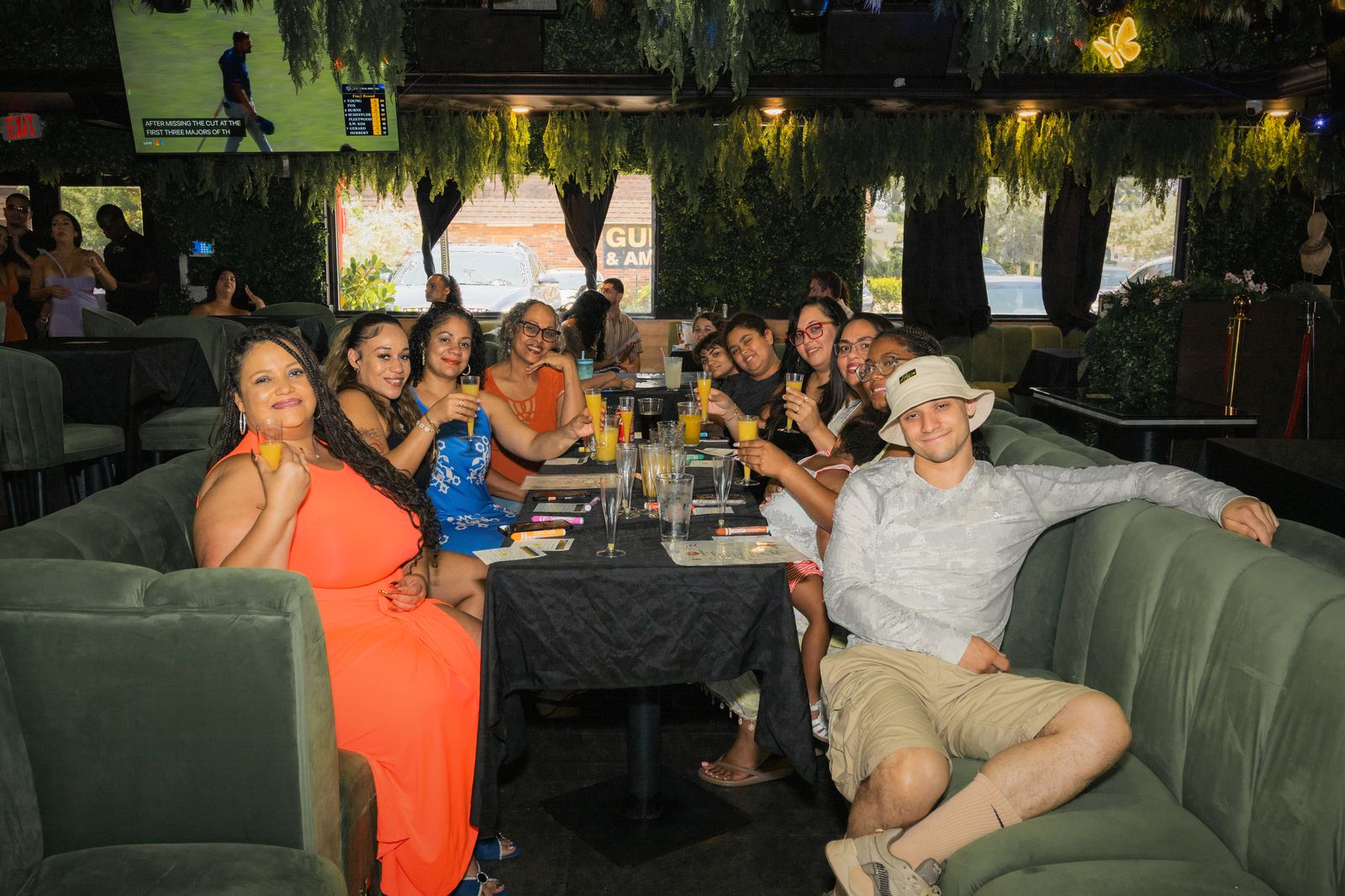 A large group celebrating at a long table in Zen's green velvet booths